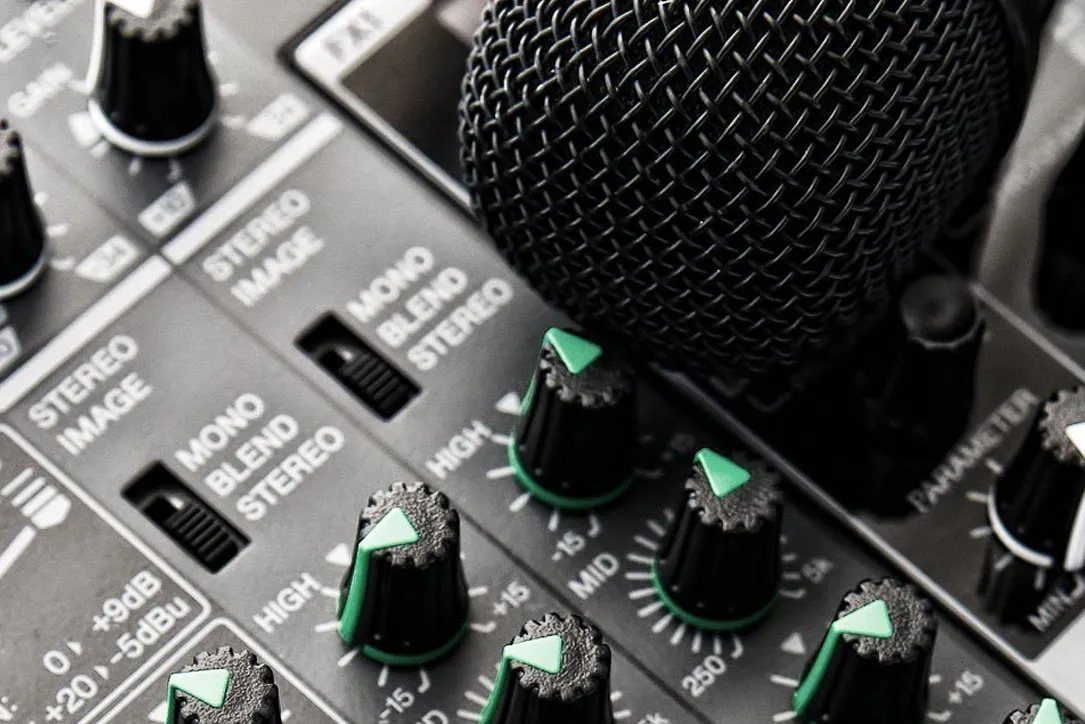 Close-up of audio mixer control panel with black knobs featuring green pointers and labels for stereo image and mono blend settings.